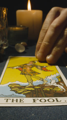 Vertical-Video-Close-Up-Shot-Of-Person-Giving-Tarot-Card-Reading-Laying-Down-The-Fool-Card-On-Table